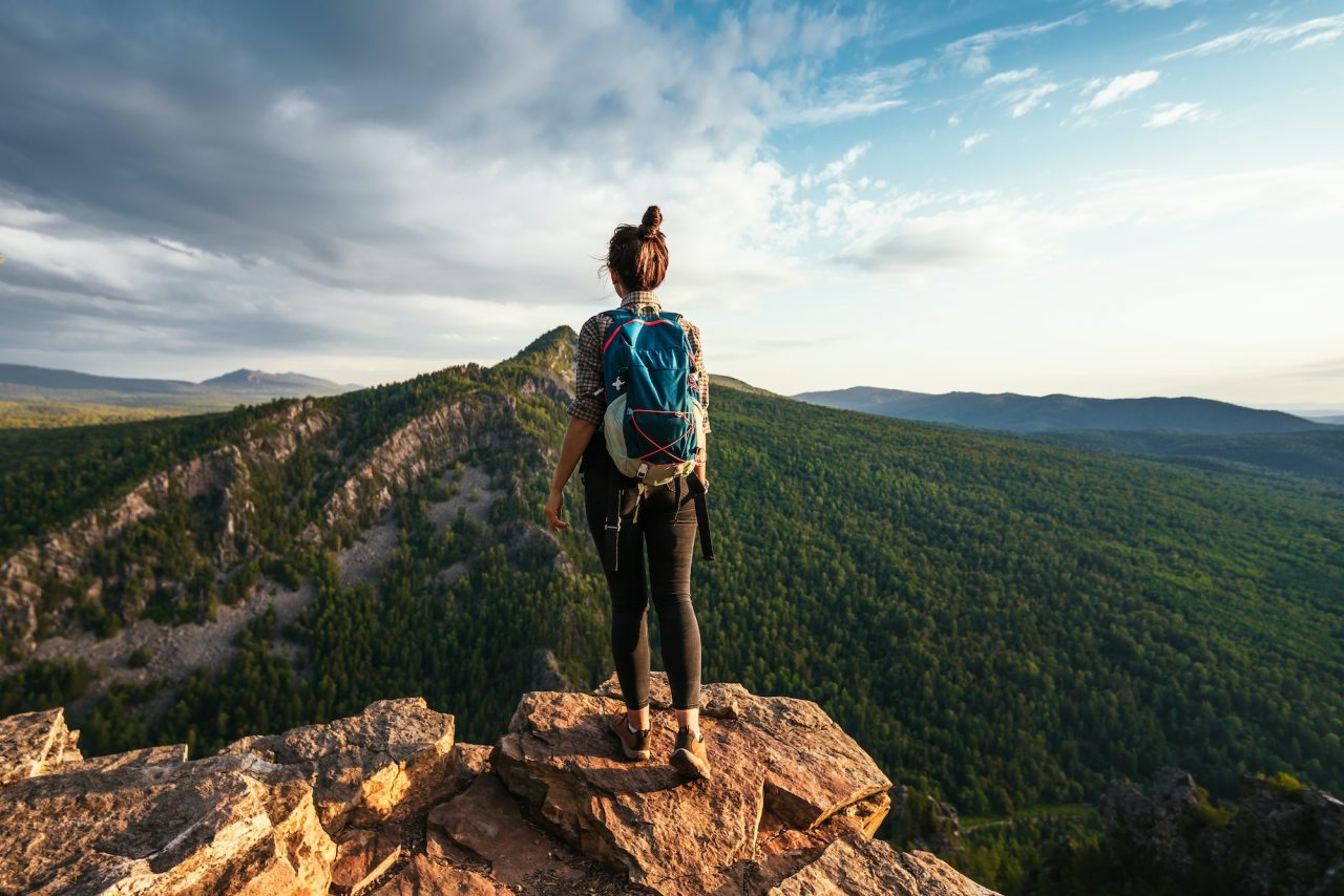 a-young-tourist-girl-with-a-backpack-enjoys-the-sunset-from-the-top-of-the-mountain.jpg